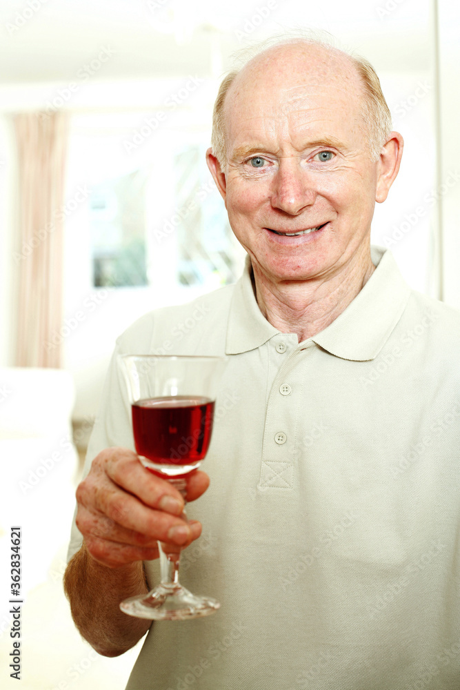 Senior man smiling while holding a glass of red wine Senior man smiling while holding a glass of red wine