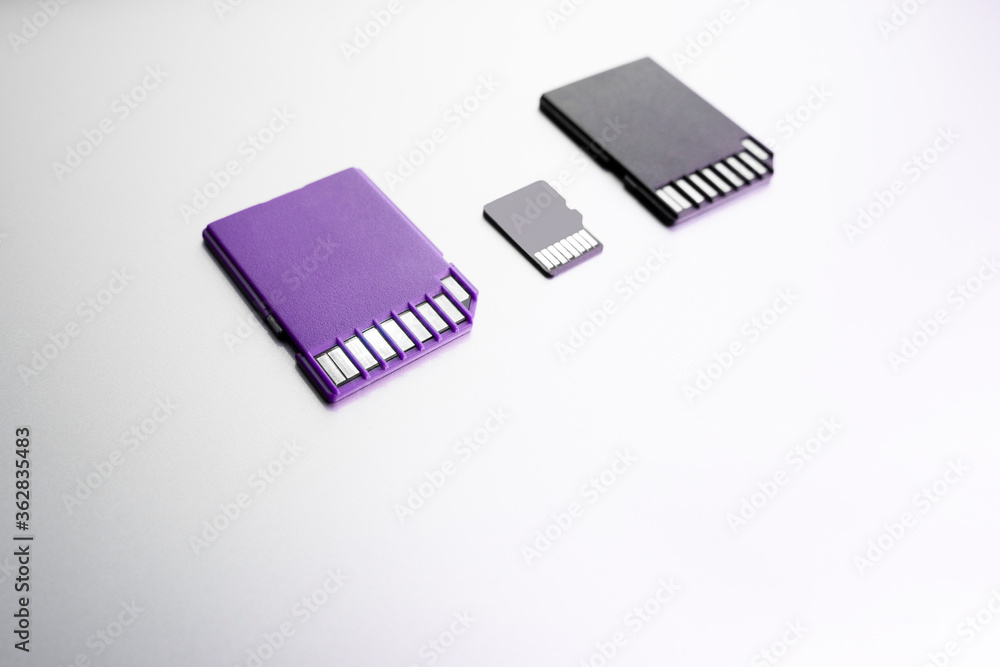 purple and black memory cards on white surface, selective focus. black flash memory card on wood texture concept. purple and black memory cards on white surface, selective focus. black flash memory card on wood texture concept.