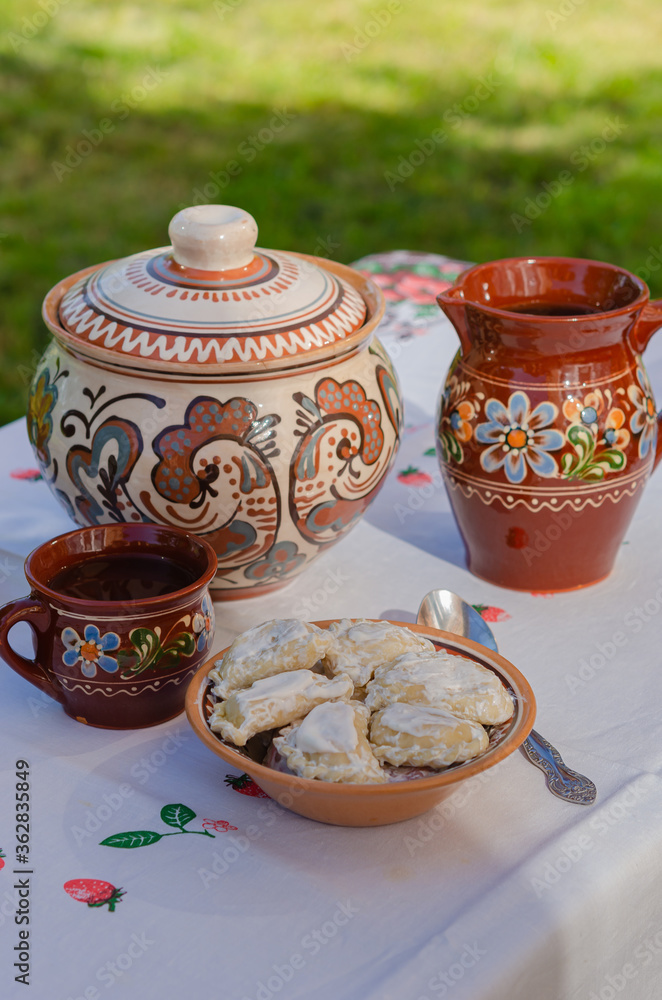 Homemade pierogi in clay ethnic Ukrainian dishes on a table in the summer garden. Homemade pierogi in clay ethnic Ukrainian dishes on a table in the summer garden.