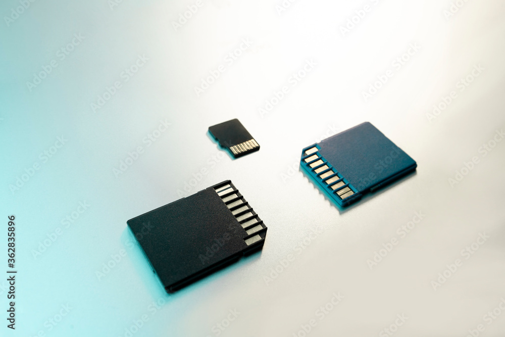 close-up of three memory cards for digital cameras and devices and on a gray metal surface, selective focus, green filter. close-up of three memory cards for digital cameras and devices and on a gray metal surface, selective focus, green filter.