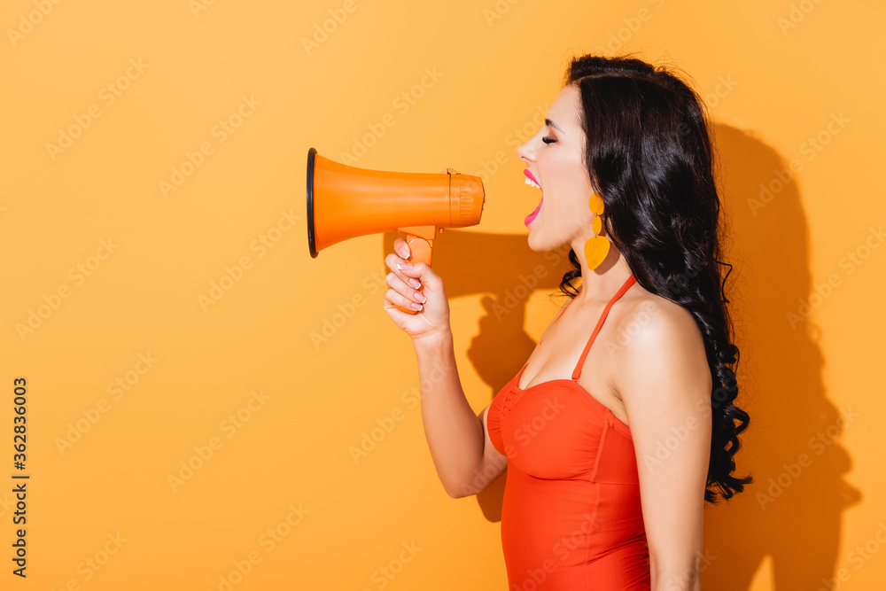 profile of young woman in swimsuit screaming in megaphone on orange profile of young woman in swimsuit screaming in megaphone on orange