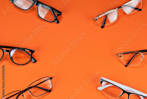 Different types of glasses on an orange background close up. Glasses with rectangular and round frames. Layout for design. Space for text and free space near the object. photo