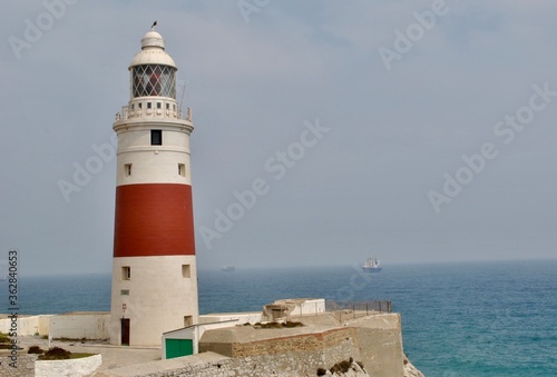 Lighthouse Amidst Sea And Buildings Against Sky
