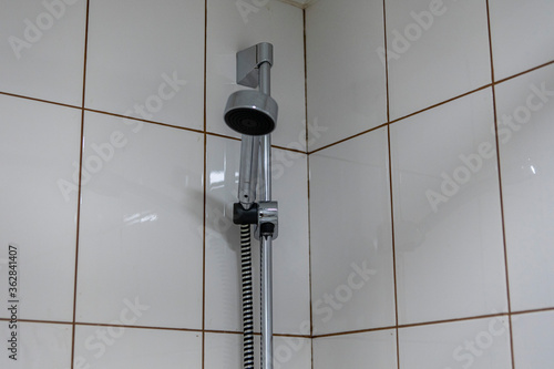 Shower head on a background of white tiles. Plumbing in hotel room