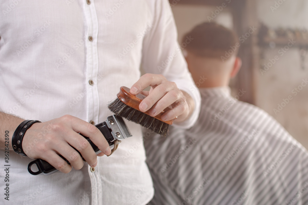 Barber cleaning electric hair clipper at barber shop.