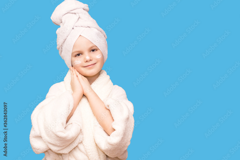 Spa skin care beauty girl wearing hair towel and white coat after beauty treatment with cream on her face under eyes. Beautiful child girl with perfect skin Spa skin care beauty girl wearing hair towel and white coat after beauty treatment with cream on her face under eyes. Beautiful child girl with perfect skin