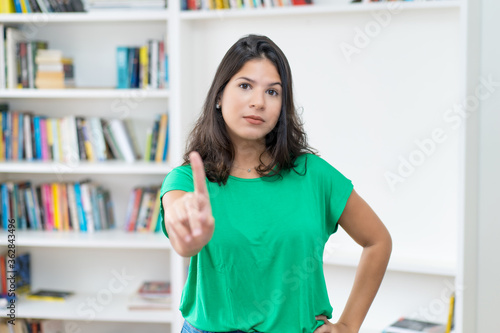 Latin american young adult woman with long dark hair gesturing stop