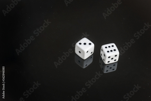 Two white dices with reflections on black background. Numbers from 1 to 6 shown in order. Abstract concept of chance, luck, gambling.