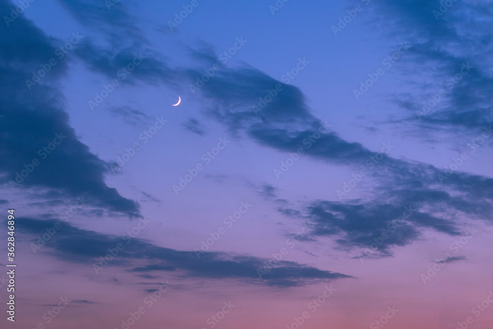 Crescent moon on night blue sky with clouds. Nature background.