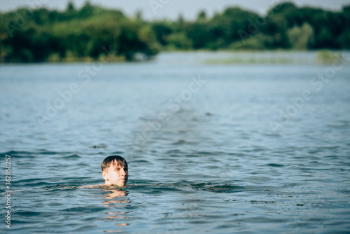 Boy swimming in the lake in summer-view from the back © kulkann