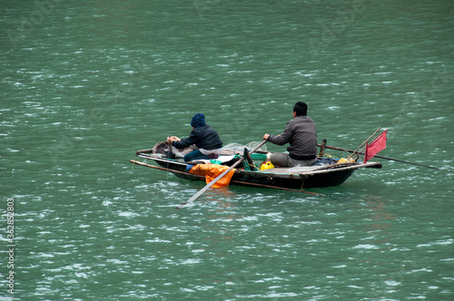 Ha Long Bay Vietnam, local men in small wooden boat fishing sustainable
