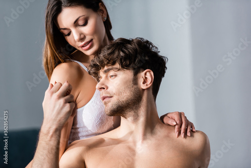 Shirtless man holding hand of beautiful woman