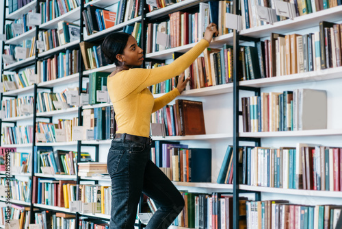 Black student taking book from bookshelf