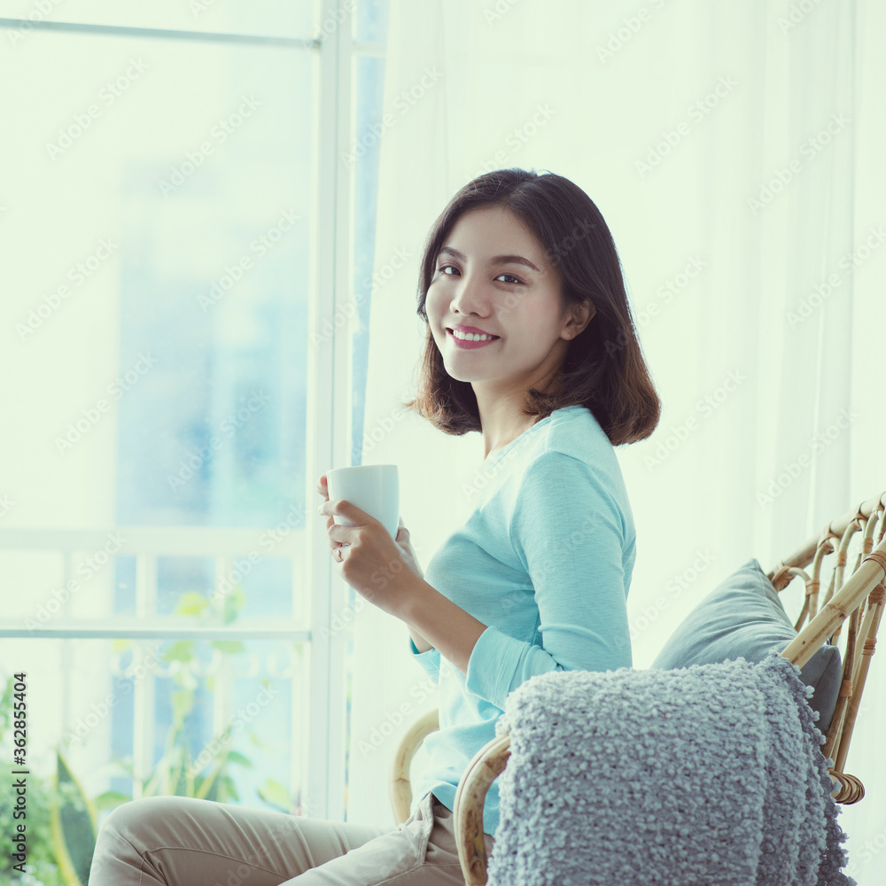 young Asian woman sitting behind the window and drinking coffee in the morning. young Asian woman sitting behind the window and drinking coffee in the morning.