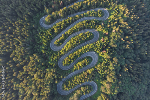 Aerial view of beautiful mountain road crossing a green forest © alexionutcoman