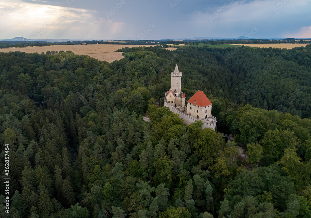 Aerial view of a medieval castle, Kokorin. Fortified palace with a tower and a wall standing on a hill covered by trees.Tourist spot. Castles in the Central Bohemian Region, Czech republic. Aerial view of a medieval castle, Kokorin. Fortified palace with a tower and a wall standing on a hill covered by trees.Tourist spot. Castles in the Central Bohemian Region, Czech republic.