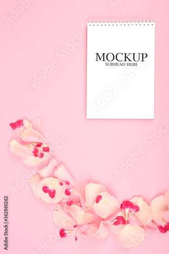 mockup of white paper and pink flowers on a pink background © SYARGEENKA