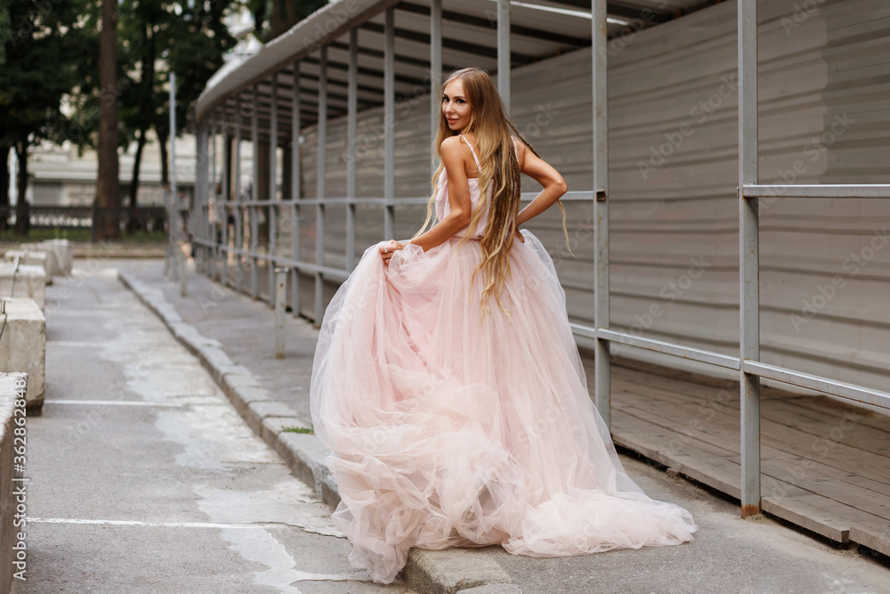 Fototapeta premium Bride in pink wedding dress runs off street town