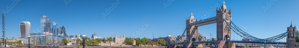 Panorama view of the Tower bridge over Thames river on a sunny day with tourists. City Financial district skyscrapers and Tower of London in the background.
