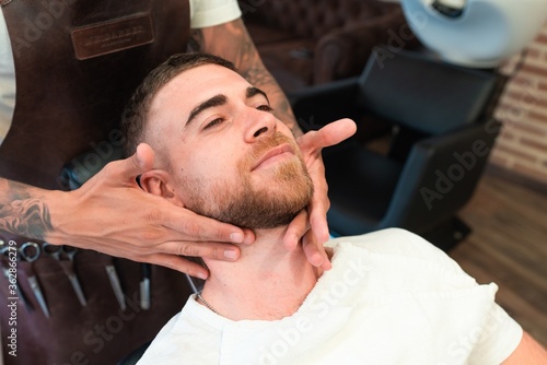 Bilde på lerret Closeup of a hairdresser applying aftershave on the customer's face in a barbers