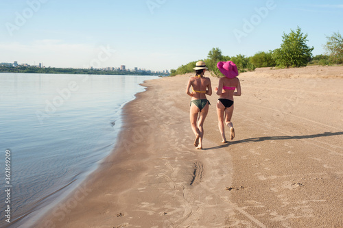two girls run off into the distance on a run on the beach. Sports recreation