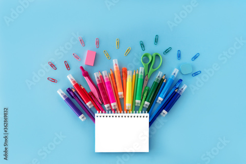 Wallpaper Mural Back to school background with opened notepad and variety of school supplies in rainbow colors on pastel blue backdrop. Flat lay. Close-up. Copy space. Torontodigital.ca