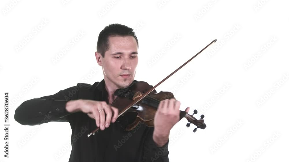 handsome violinist in a black shirt masterfully performs a beautiful slow composition on a classical violin. Symphonic music concert. Isolated. Medium long shot handsome violinist in a black shirt masterfully performs a beautiful slow composition on a classical violin. Symphonic music concert. Isolated. Medium long shot