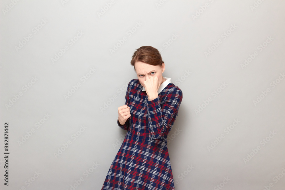 Portrait of angry young woman raising fist up in threatening gesture Portrait of angry young woman raising fist up in threatening gesture