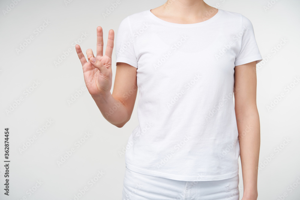 Cropped shot of raised females hand froming sign with fingers while meaning number seven on sign language, isolated against white background in casual clothes Cropped shot of raised females hand froming sign with fingers while meaning number seven on sign language, isolated against white background in casual clothes