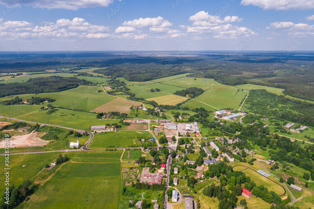 Aerial view of cloudy sunny day. Countryside surrounded by green fields, rivers and trees.