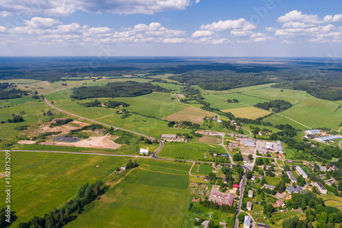 Aerial view of cloudy sunny day. Countryside surrounded by green fields, rivers and trees.