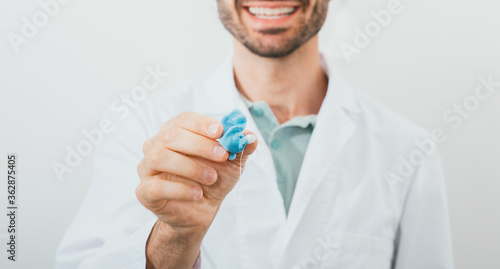 Fotografie Positive audiologist holding in his hands molded individual hearing aid earmolds for his patient, close-up