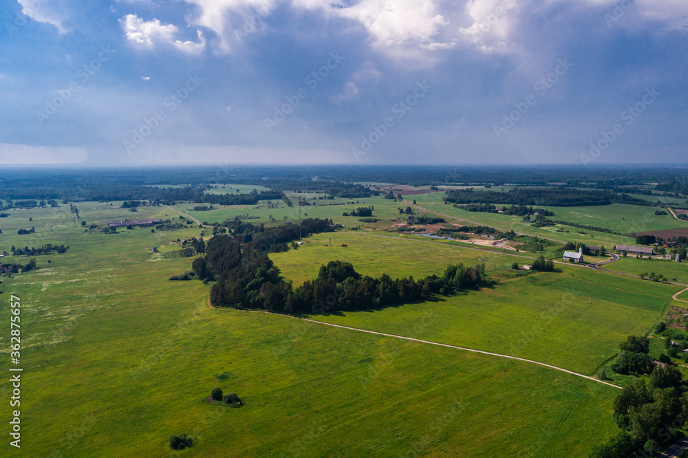 Aerial view of cloudy sunny day. Countryside surrounded by green fields, rivers and trees.