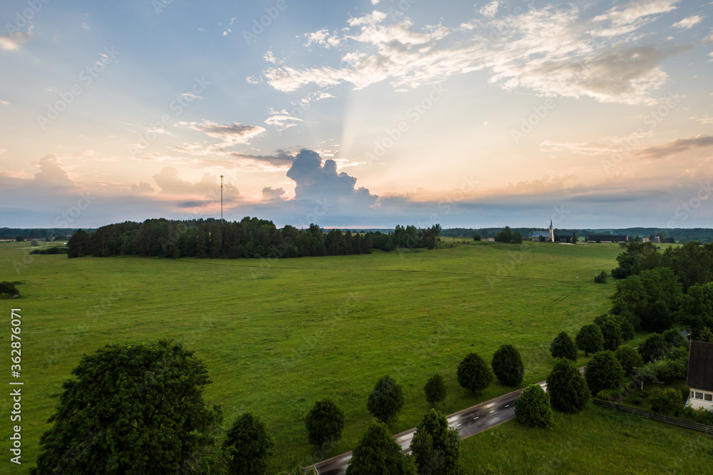 Fototapeta premium Aerial view of amazing sunset at summer season. Nature landscape. Landscape surrounded by green fields, rivers and trees.