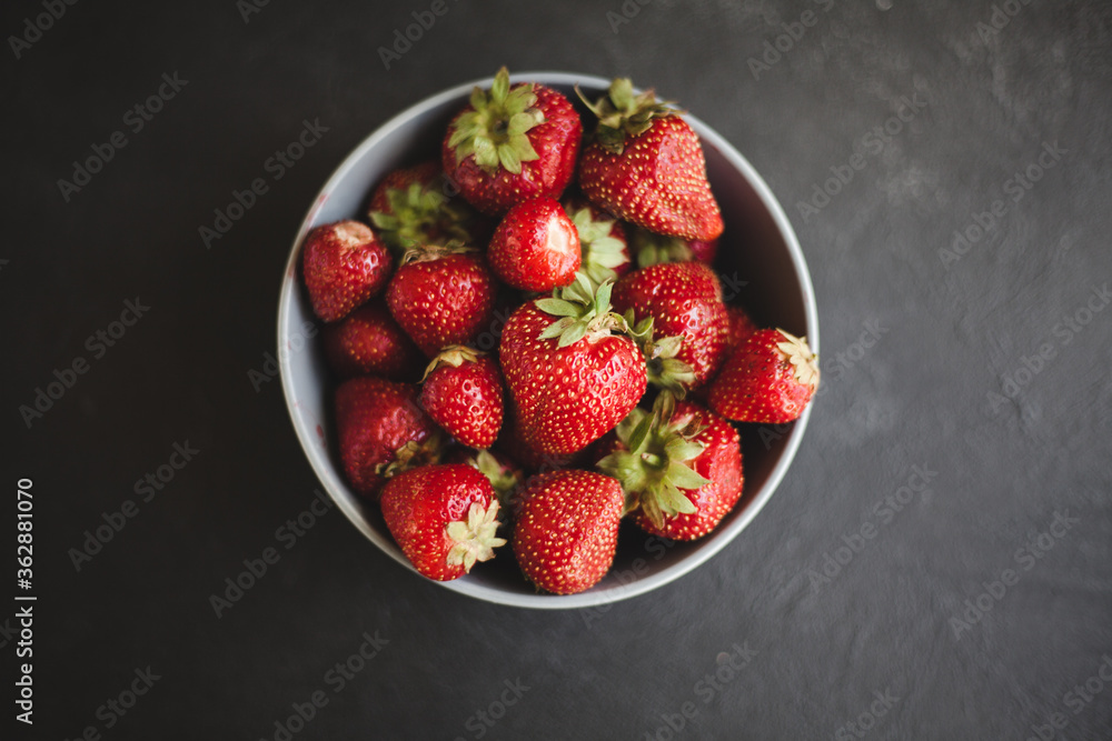 Fresh ripe tasty strawberries in a black plate on a gray wooden background. Flat lay Fresh ripe tasty strawberries in a black plate on a gray wooden background. Flat lay