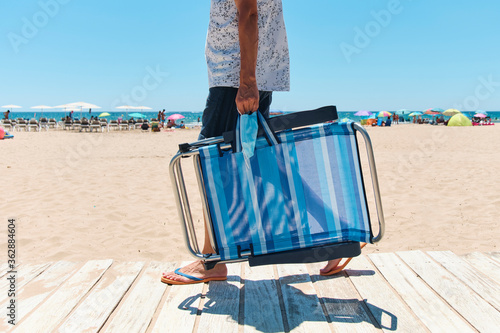 Photo man carrying a surgical mask and a deck chair