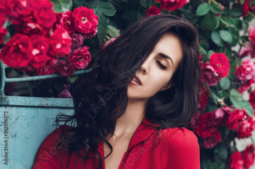 Beautiful portrait of sensual brunette woman close to red roses. Toned image © sergiophoto