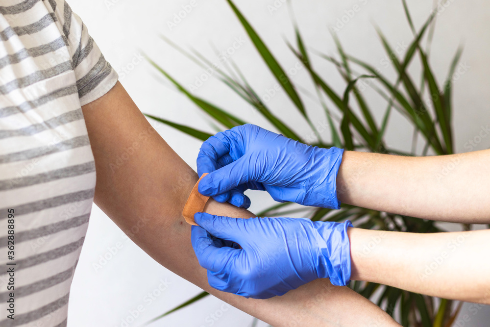 Nurse or doctor in blue rubber protective gloves putting adhesive bandage  on young woman's arm after injection of vaccine. First aid. Medical,  pharmacy and healthcare concept. Stock-Foto | Adobe Stock