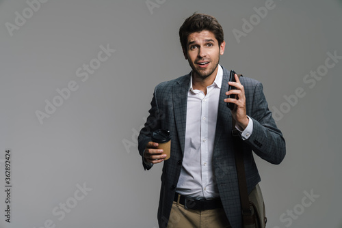 Photo of smiling businessman drinking coffee and using cellphone