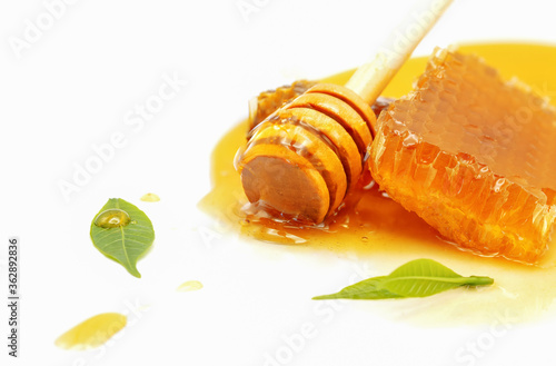 Honeycomb with honey dipper and leaf isolated on white background