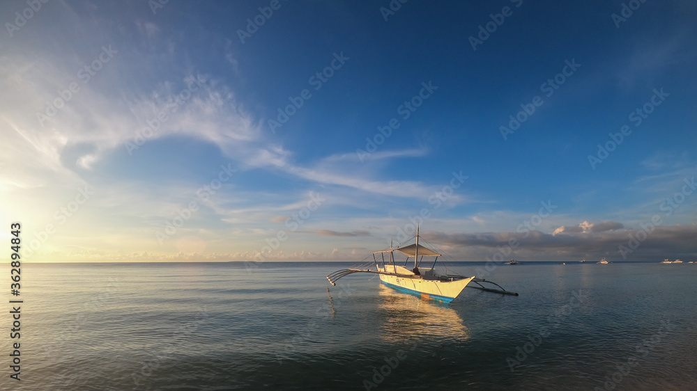fishing boat on the surface of the sea in calm at sunset
