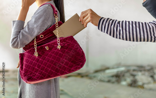 man pickpocketing a purse from woman's bag photo