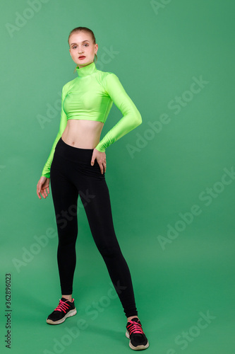 Sporting slender girl in leggings on a green background