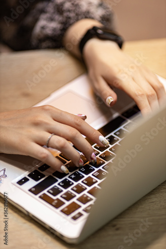womens hands typing on a laptop computer, cropped view