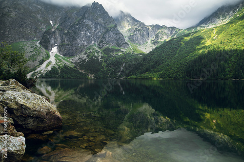 Beautiful view of green forest, hills and rocky mountains with reflection on the Morskie Oko lake, High Tatras, Zakopane, Poland