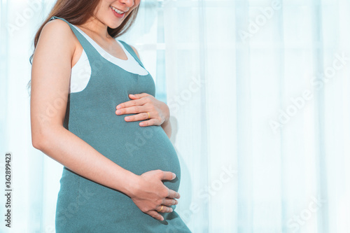 20 weeks pregnant woman in a gray dress, posing comfortably in her bedroom By standing at the edge of the window curtain and in a happy smile Free Download 20 weeks pregnant woman in a gray dress, posing comfortably in her bedroom By standing at the edge of the window curtain and in a happy smile - GFXLoad