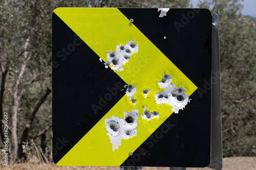Canvas Print Red road traffic sign full of bullet holes. Close up.