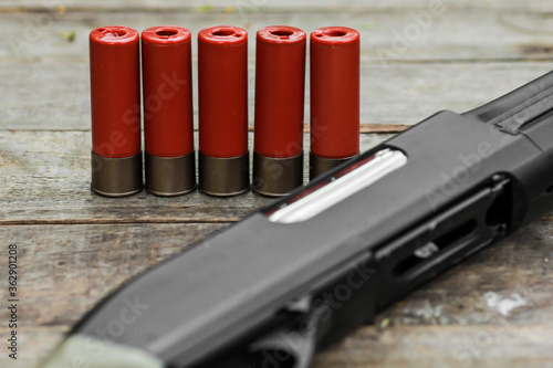 Red shotgun shells ammunition with shotgun rifle on wooden table
