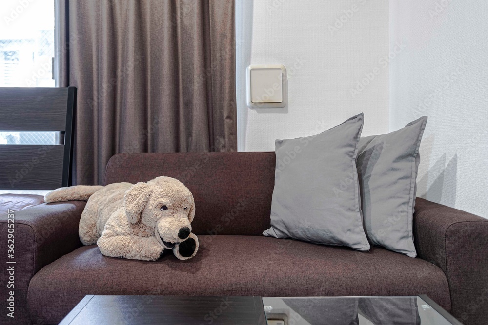 A big dog doll on a brown sofa in the living room A big dog doll on a brown sofa in the living room