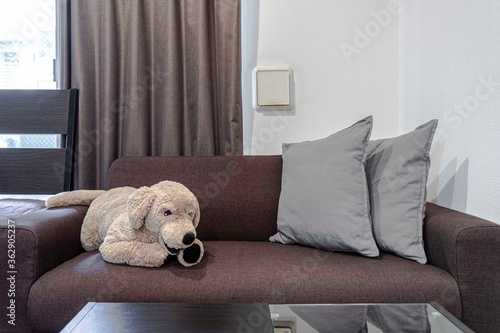 A big dog doll on a brown sofa in the living room